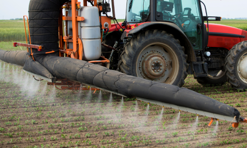 An agricultural sprayer being towed behind a tractor.